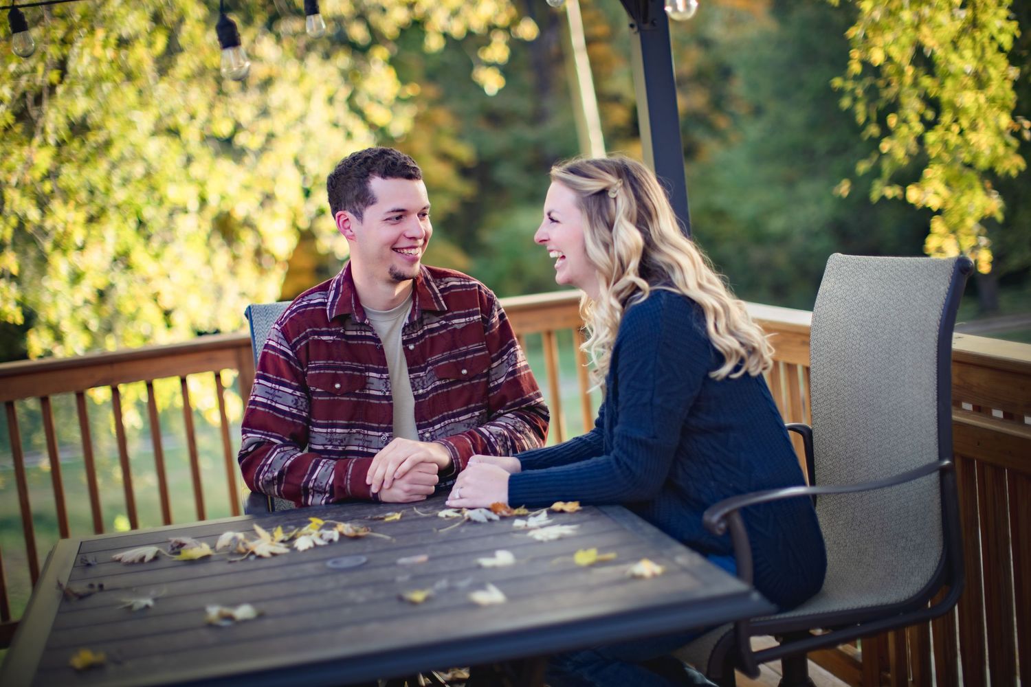Couple shares intimate conversation at outdoor patio table surrounded by fall leaves.