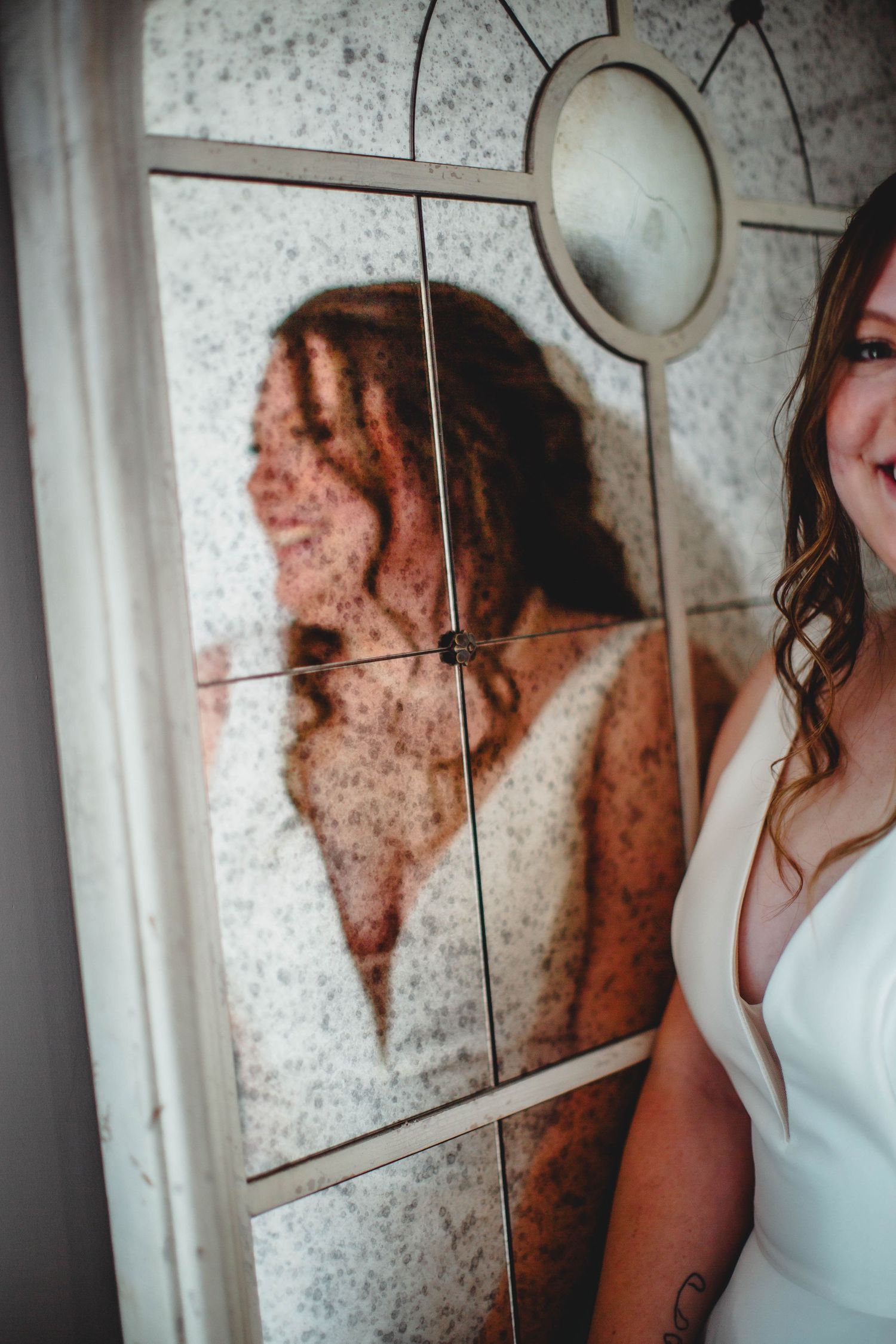 Artistic shot showing the reflection of a bride in a decorative mirror.