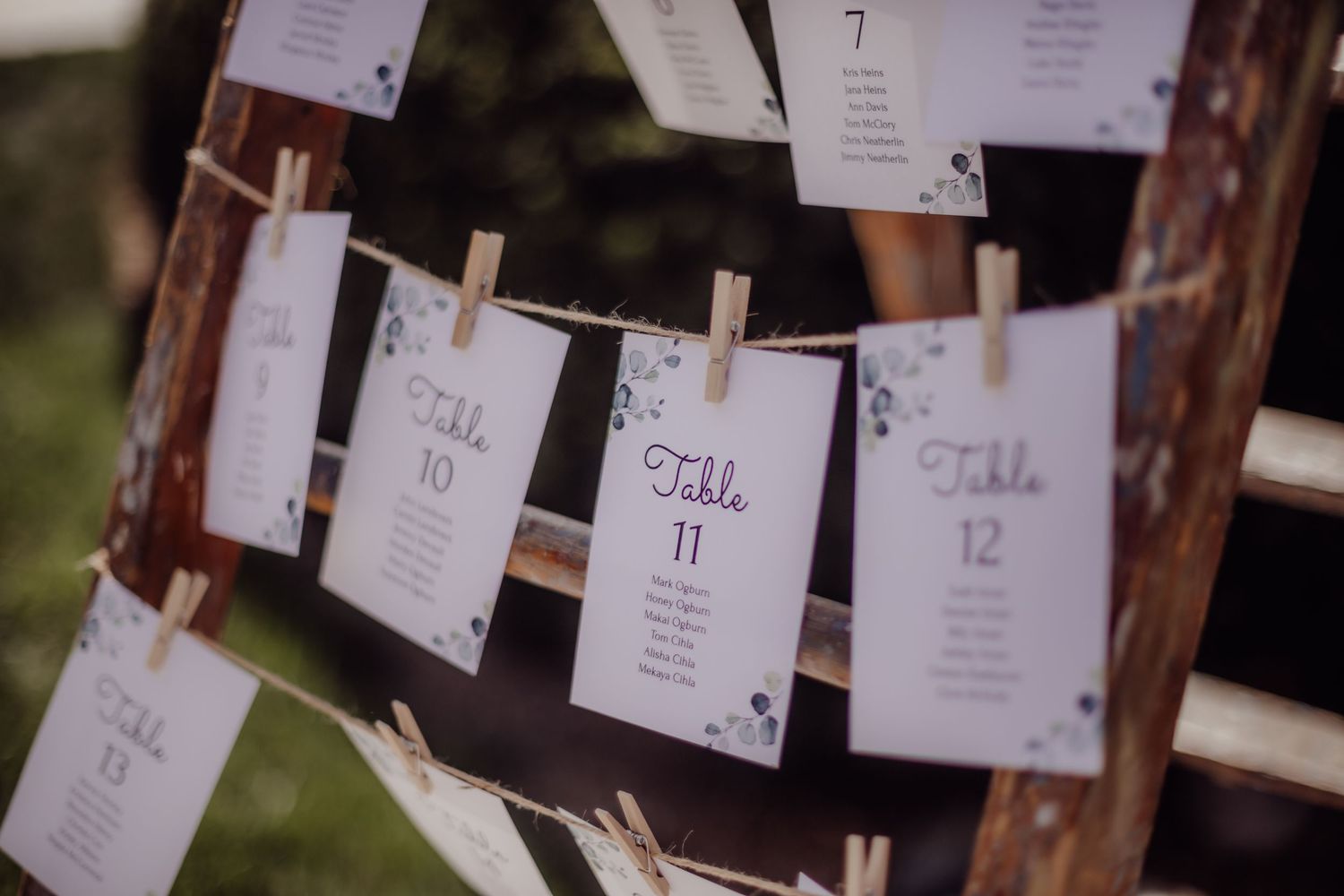 Wedding seating chart cards hung with wooden clothespins on string display.
