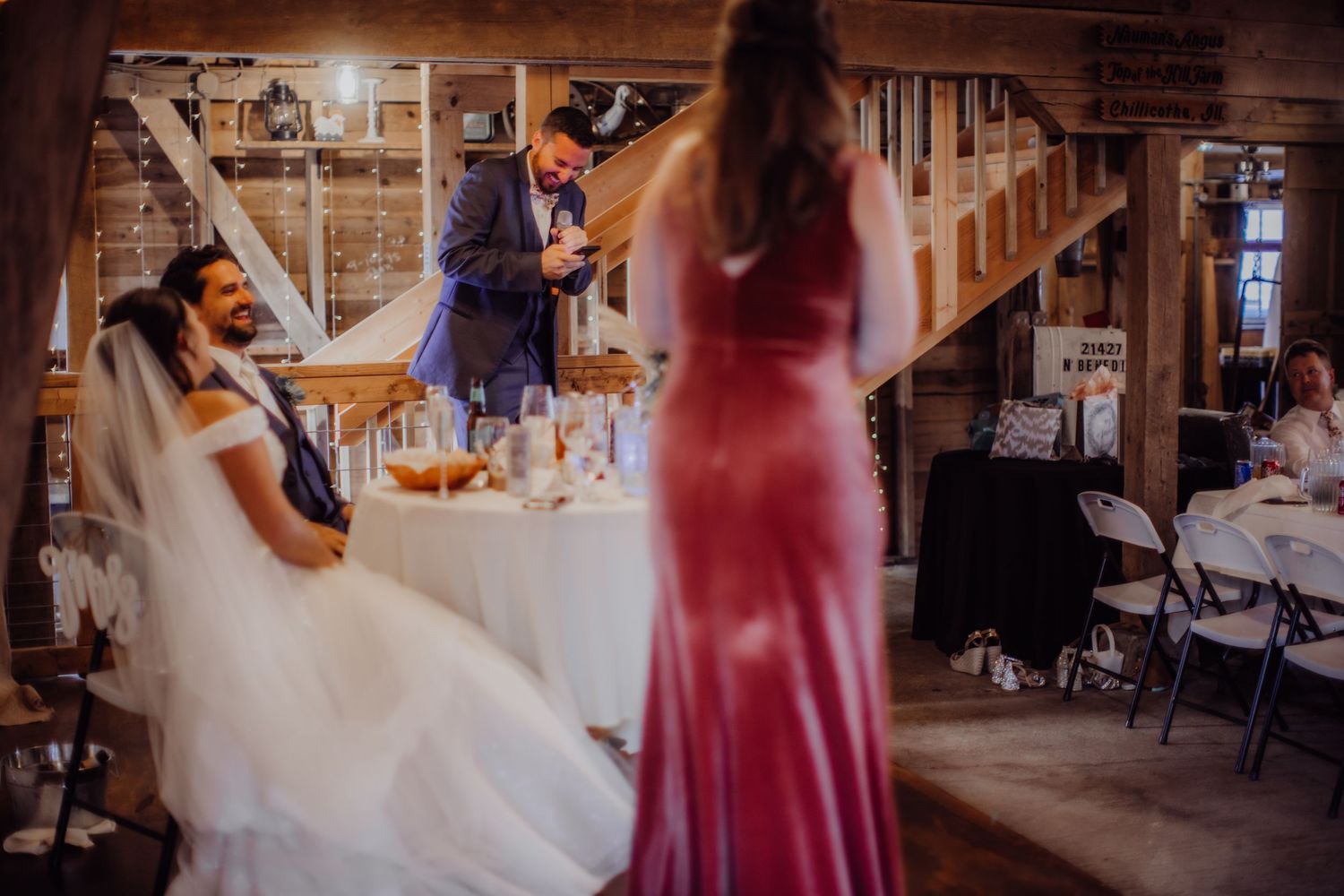 Wedding celebration continues with speeches in rustic venue as guests enjoy the reception.