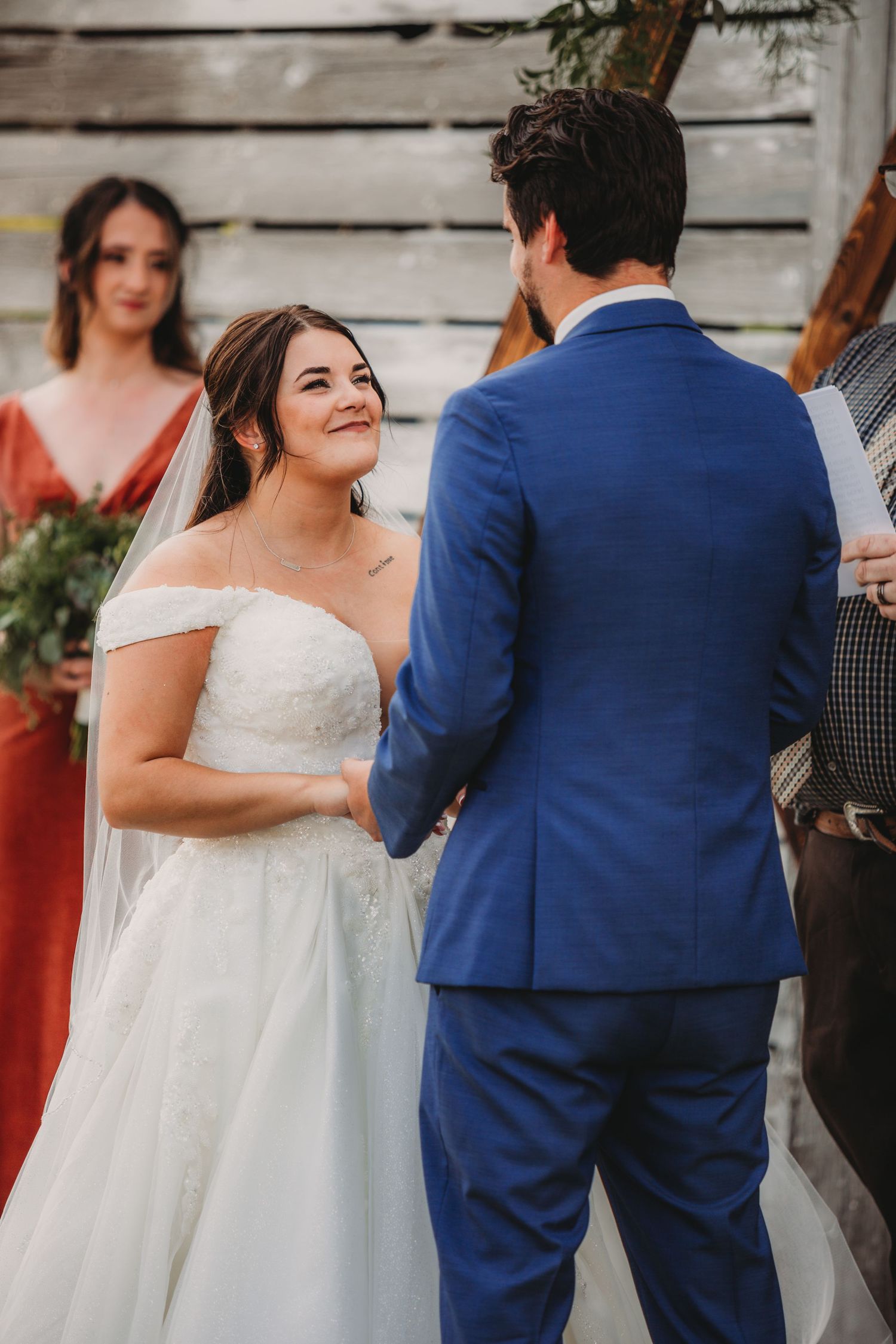 Emotional wedding ceremony moment captured against a vintage barn wall background.