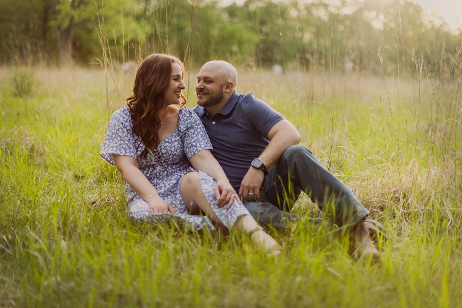 A couple shares loving glances while relaxing in a golden grass field.