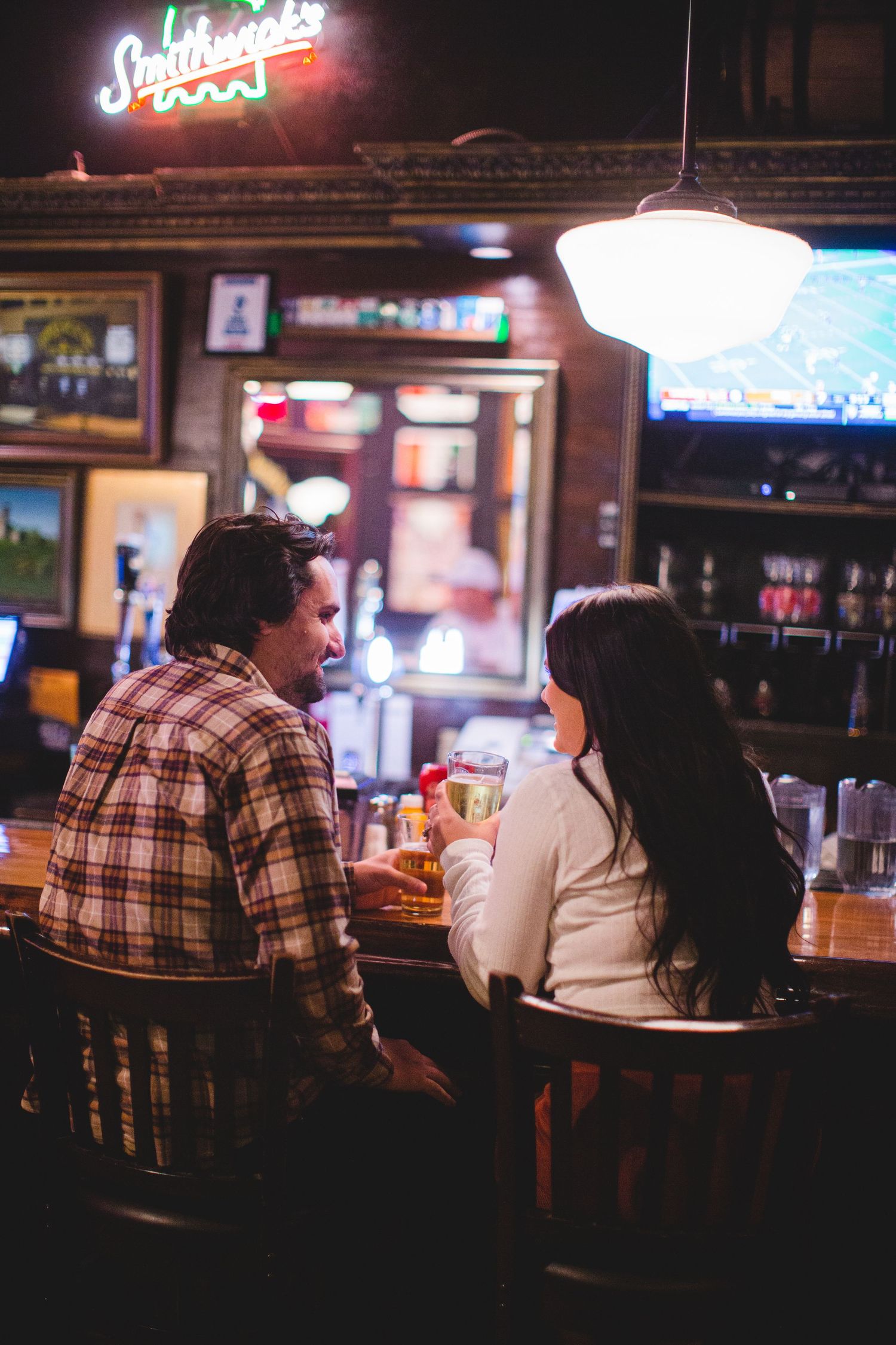 Customers relaxing at a casual sports bar with neon signage visible in the background.