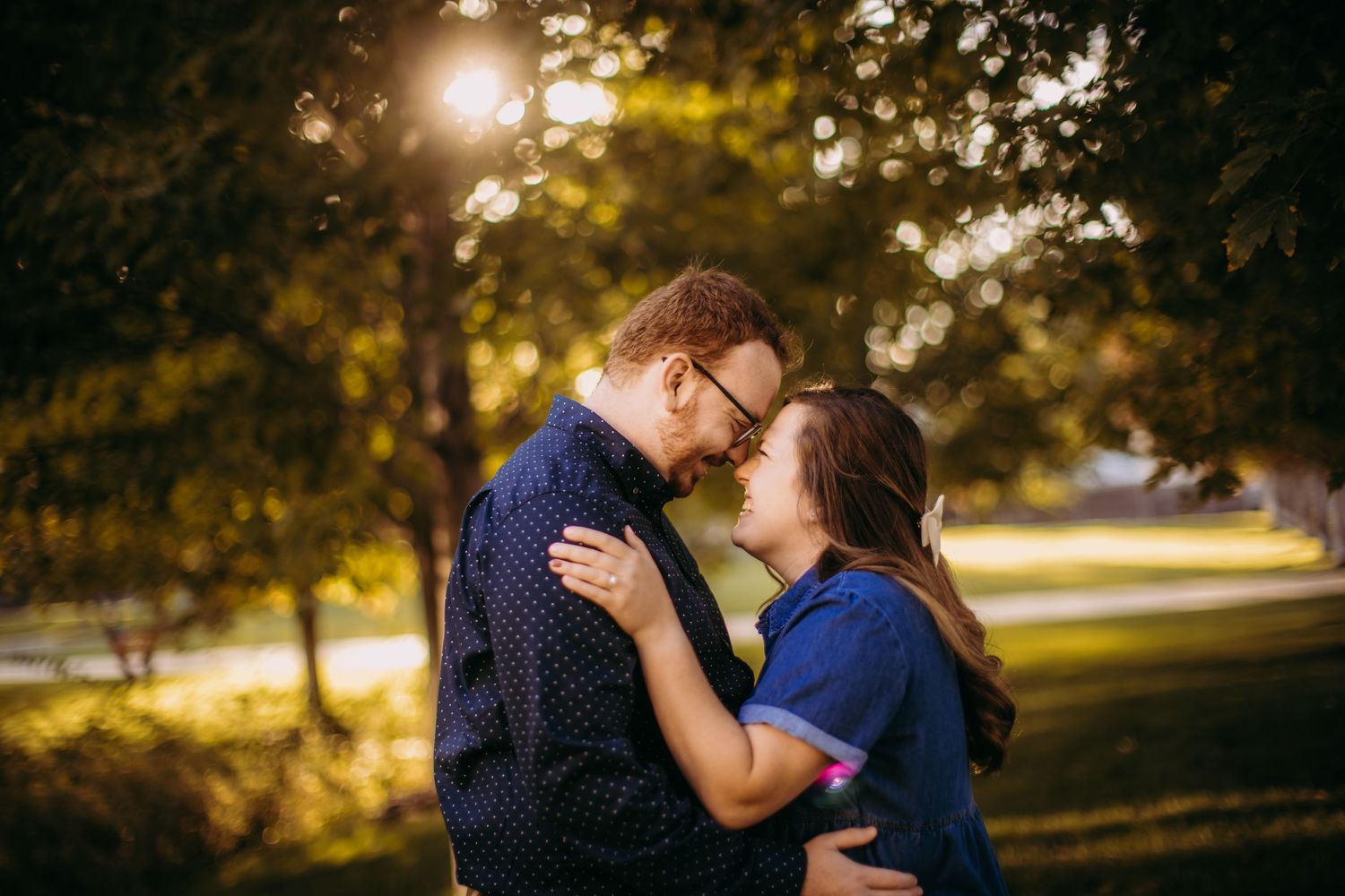 Romantic moment captured in a park with golden sunlight filtering through trees.