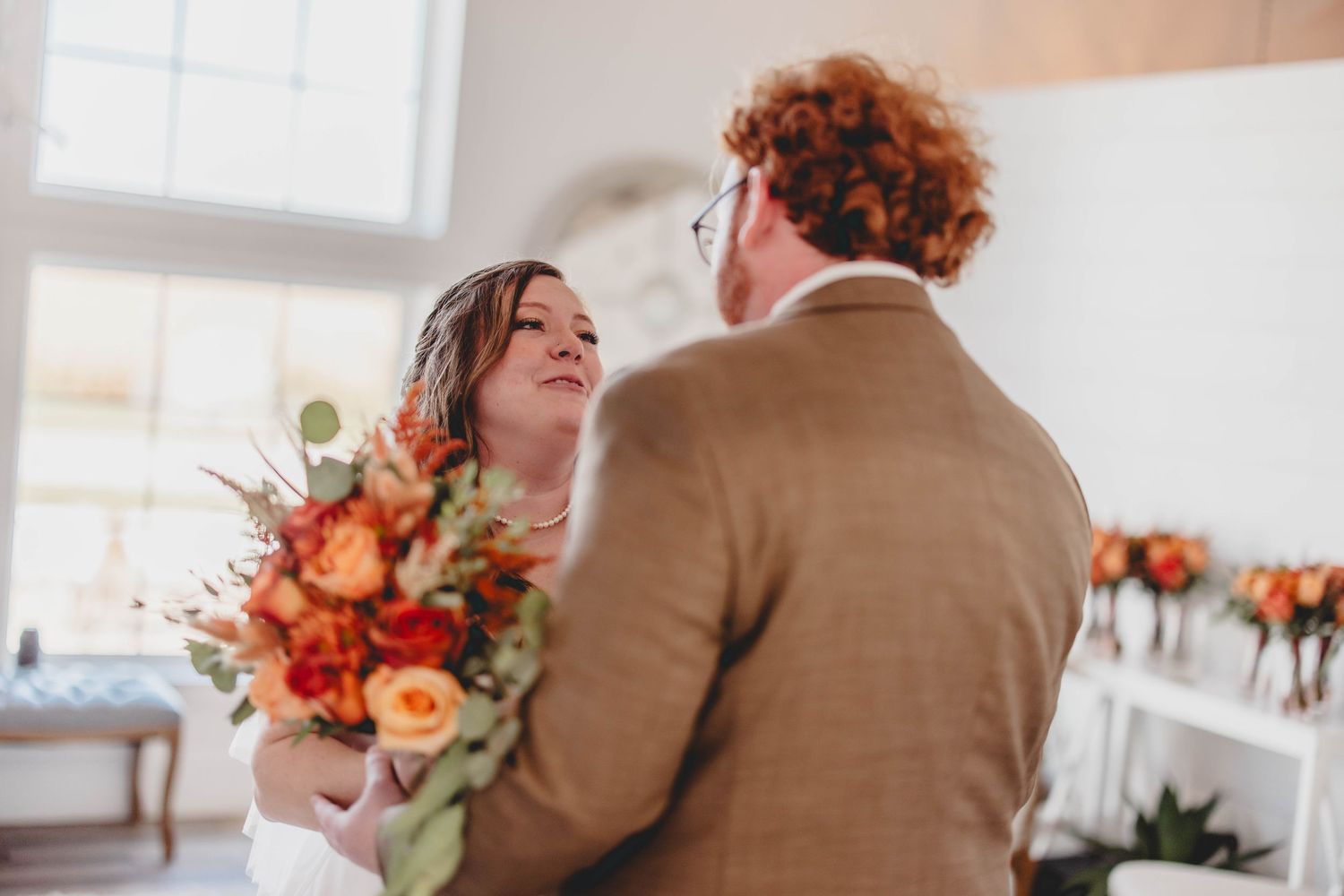 Emotional wedding scene with soft natural lighting and vibrant orange floral accents.