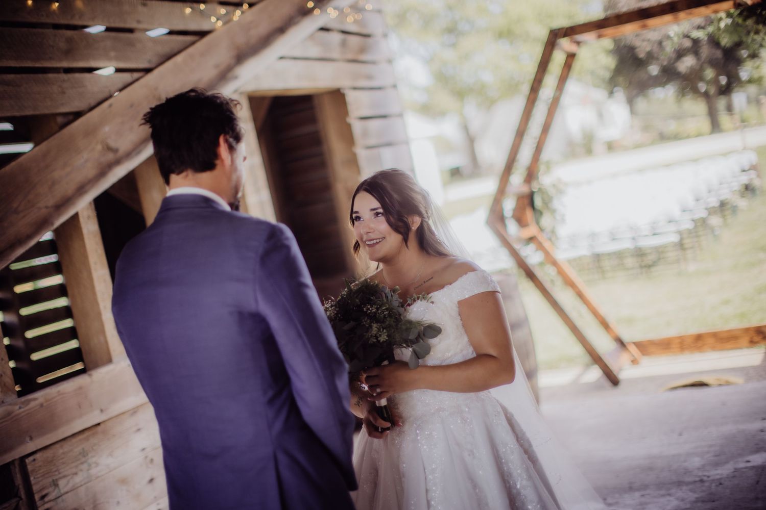 A sweet exchange between newlyweds under wooden beams with string lights.