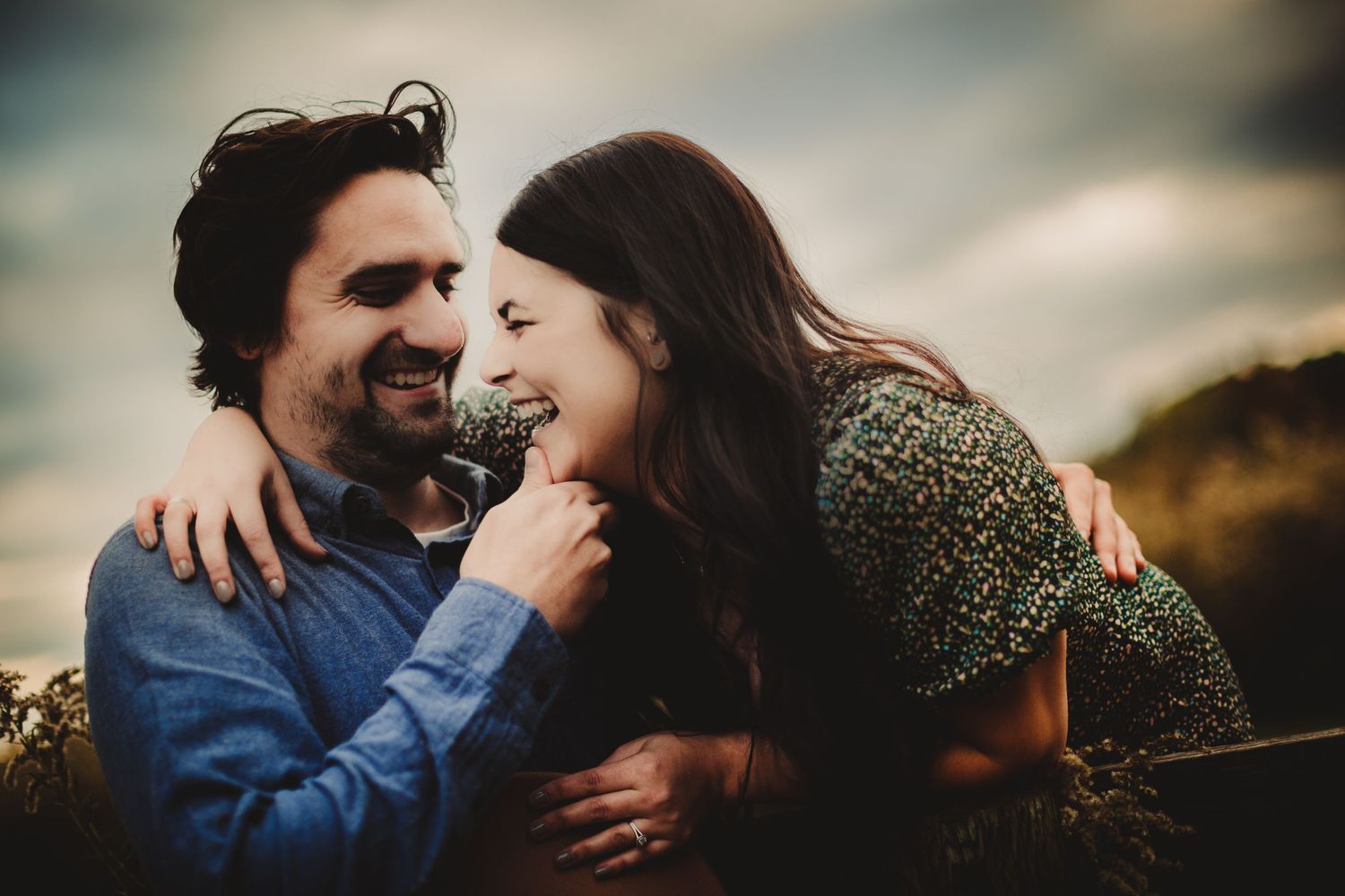 Natural light portrait of couple sharing joyful moment during sunset photoshoot.