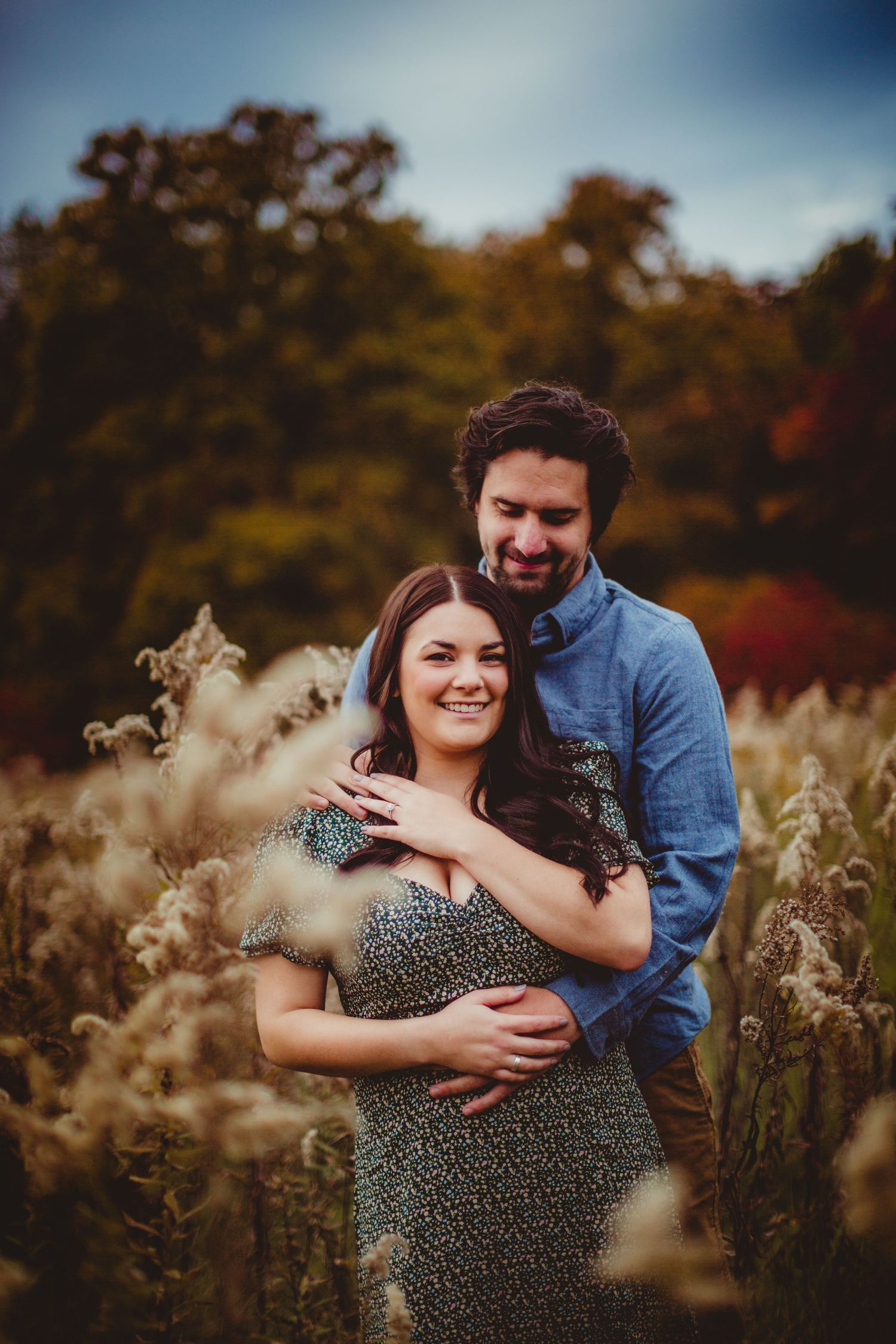 Sweet couple moment photographed against autumn foliage and tall grass.
