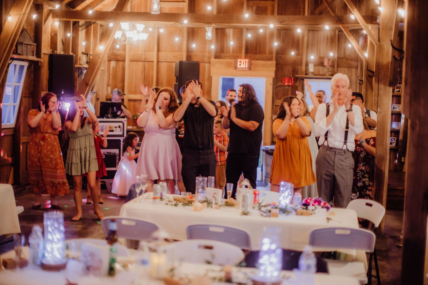 Reception celebration in a barn venue with string lights and guests enjoying the festivities.
