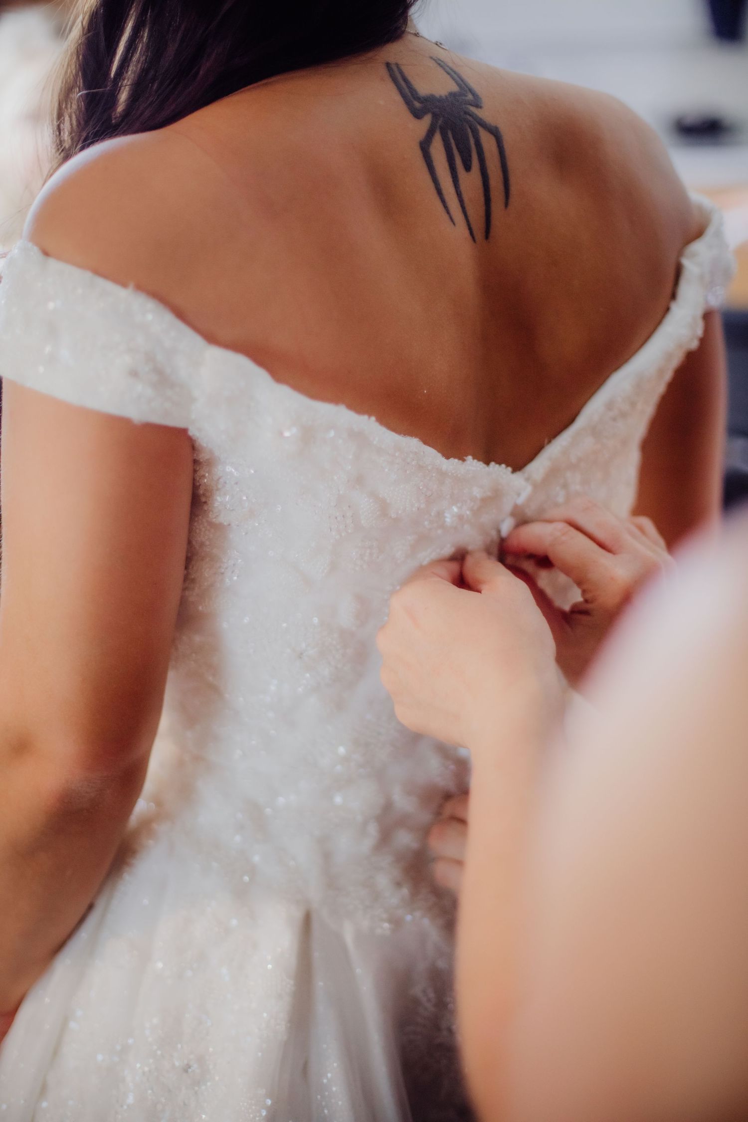 Back detail of an ornate white wedding dress being fastened.