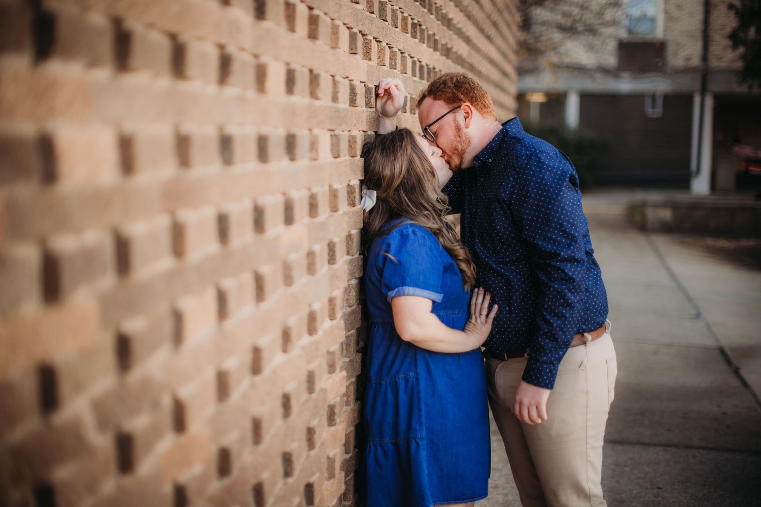 Romantic moment captured against a geometric brick wall backdrop.