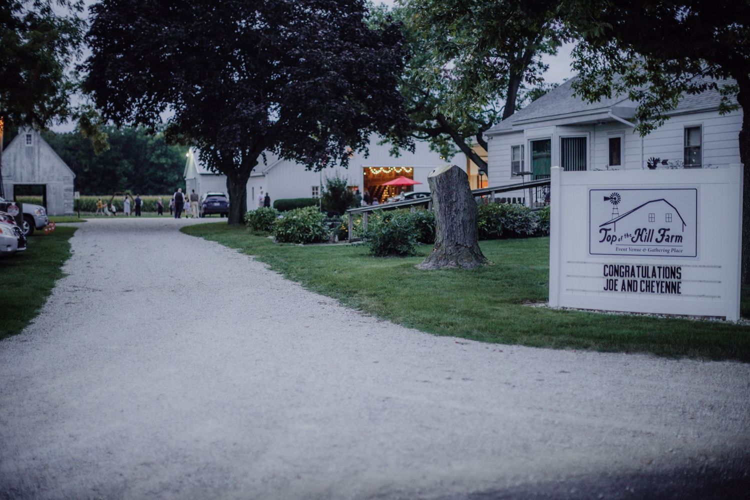 Rustic white barn and gravel pathway scenery viewed from a distance.