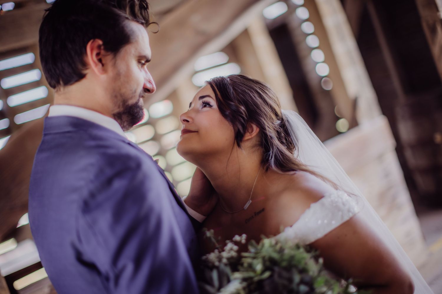 Romantic wedding portrait of couple sharing intimate moment in rustic barn venue.