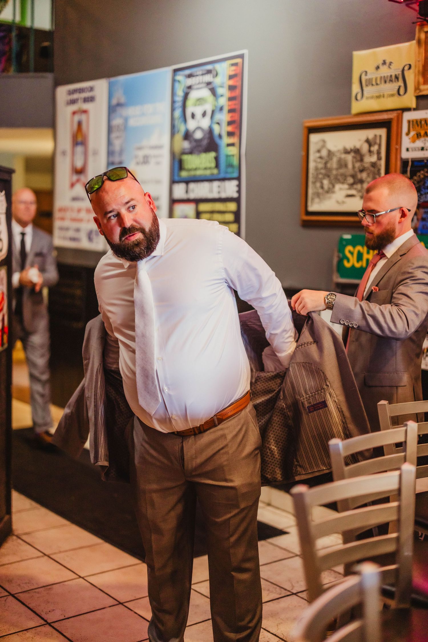 Person getting suit jacket adjusted in casual restaurant setting with tiled floor.
