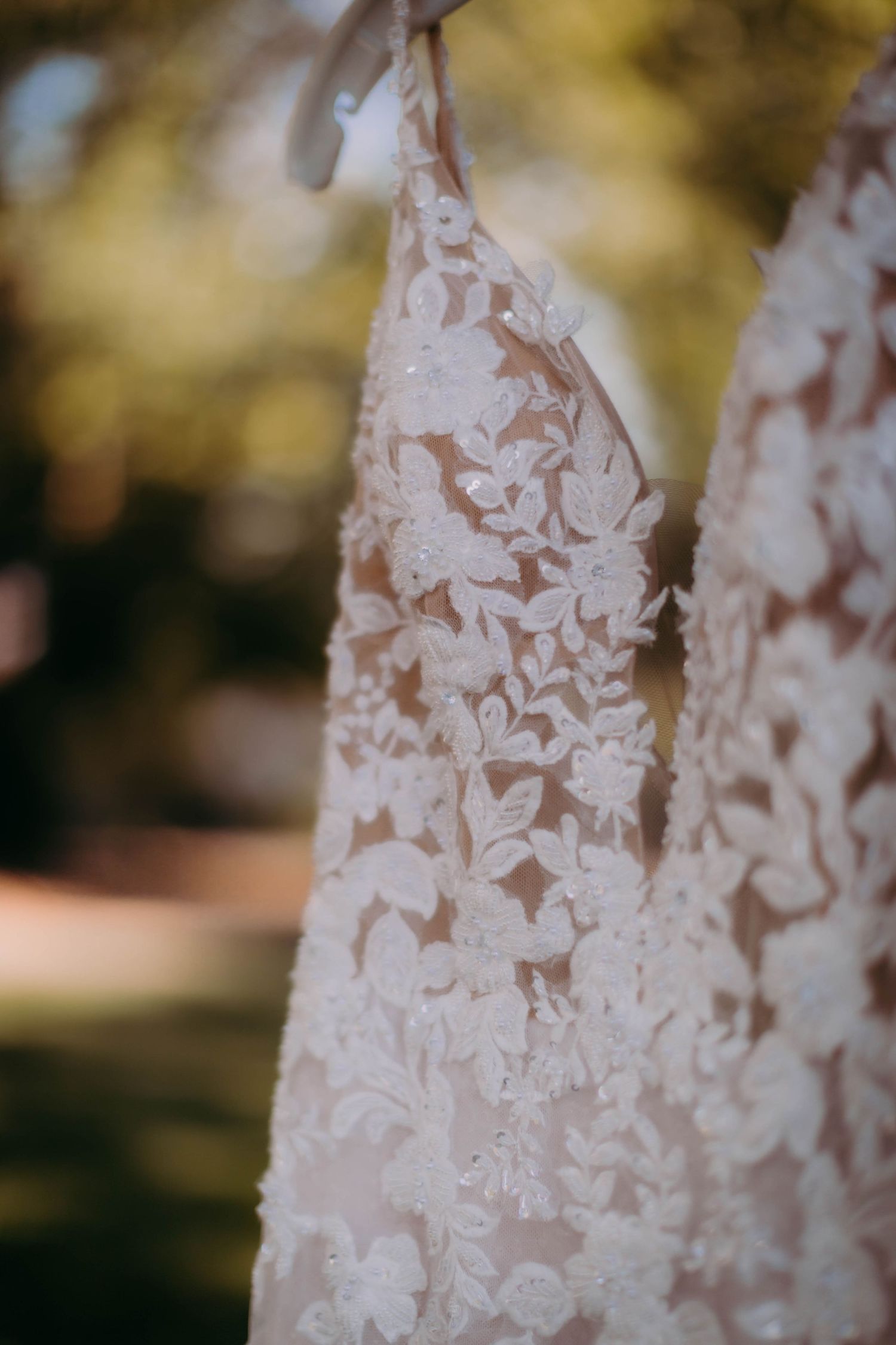 Detailed close-up of intricate floral lace pattern on a white wedding gown.