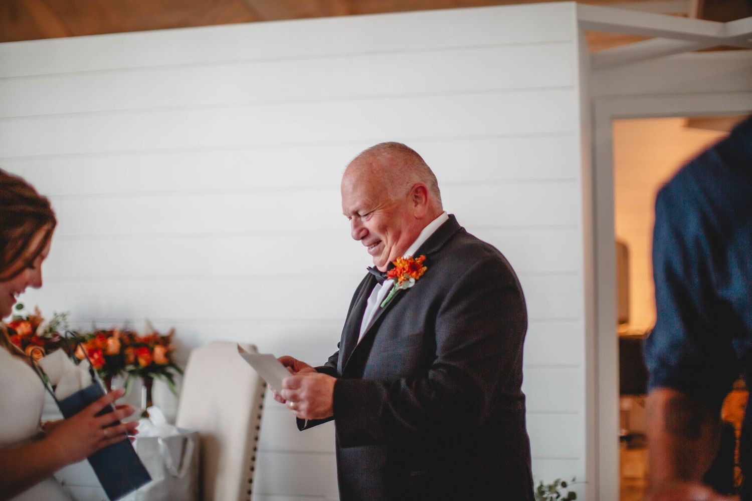 Wedding ceremony guest reads from a paper while standing in formal attire.
