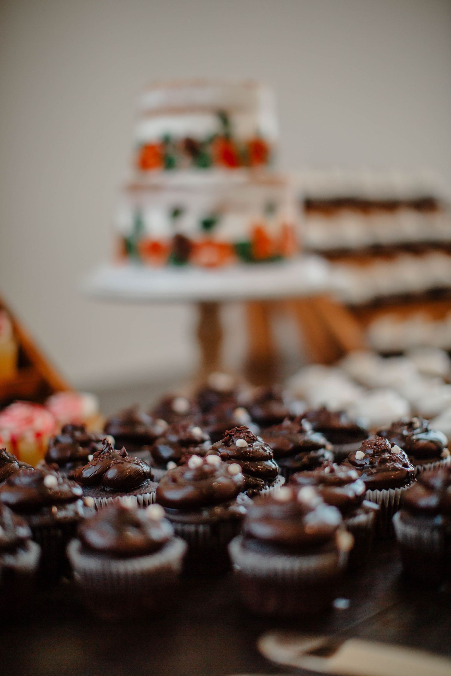 Chocolate cupcakes with frosting arranged on a dessert table with other baked goods.