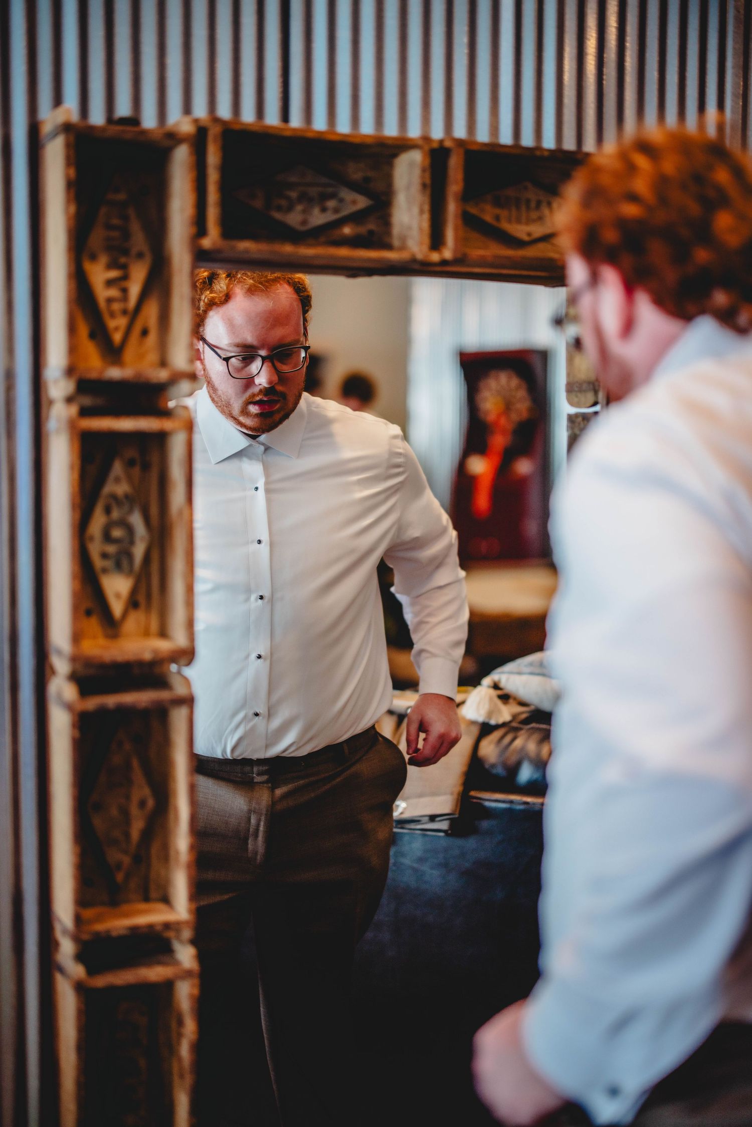 Two men in formal attire having a discussion in an industrial-styled room with wooden crates.