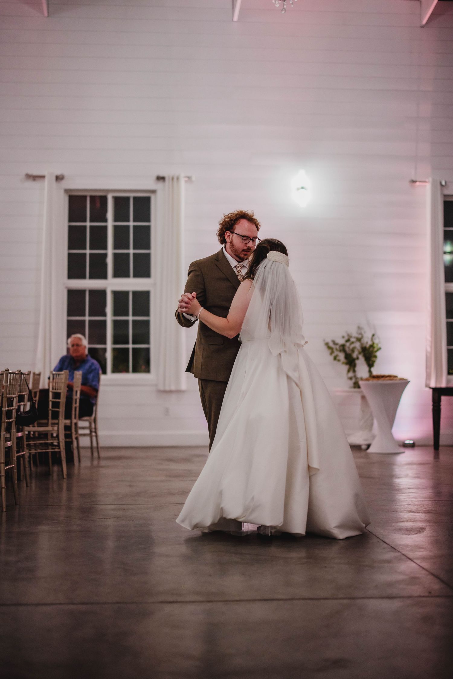 A tender moment between newlyweds during their first dance in an elegantly lit wedding venue.