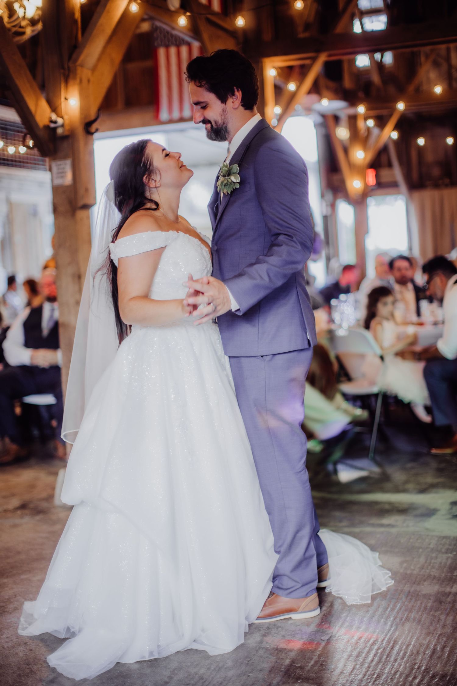 Couple dancing and laughing together during their first dance in a rustic barn venue.