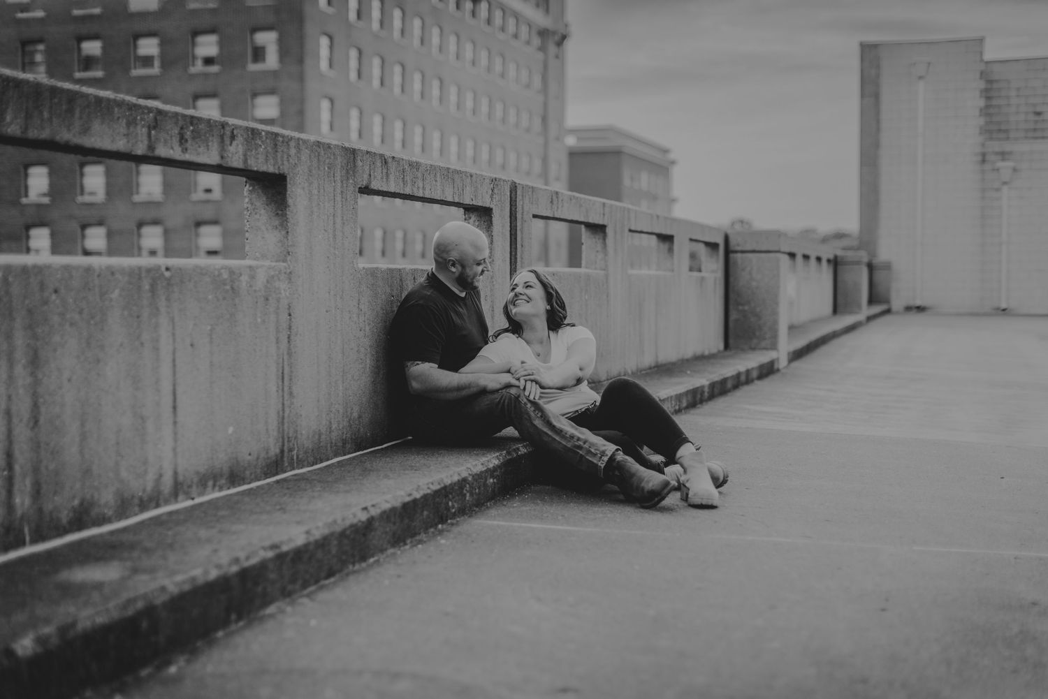 A romantic black and white photo of a couple sitting on an urban concrete ledge.