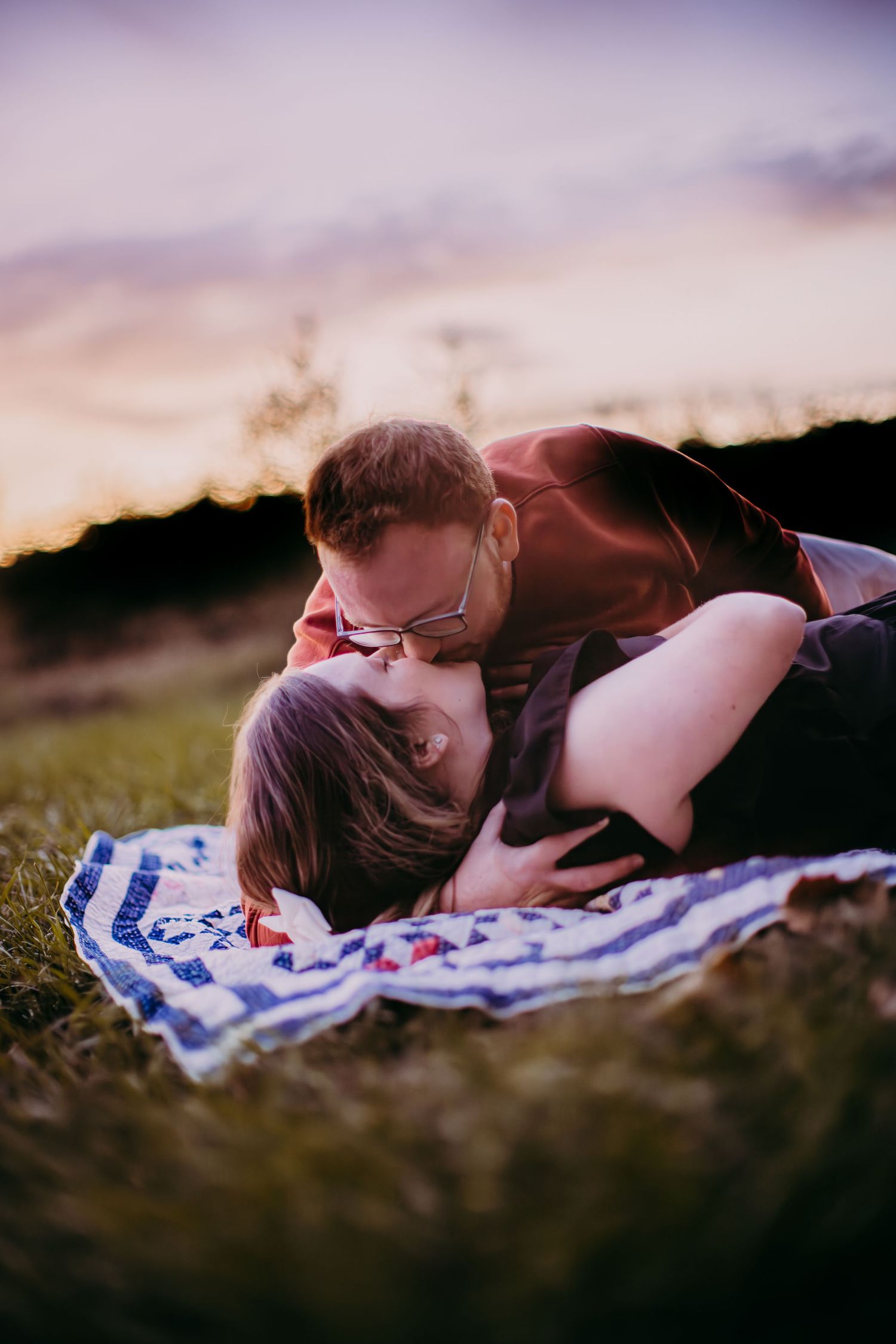 Romantic couple photography at sunset with soft purple sky in background.