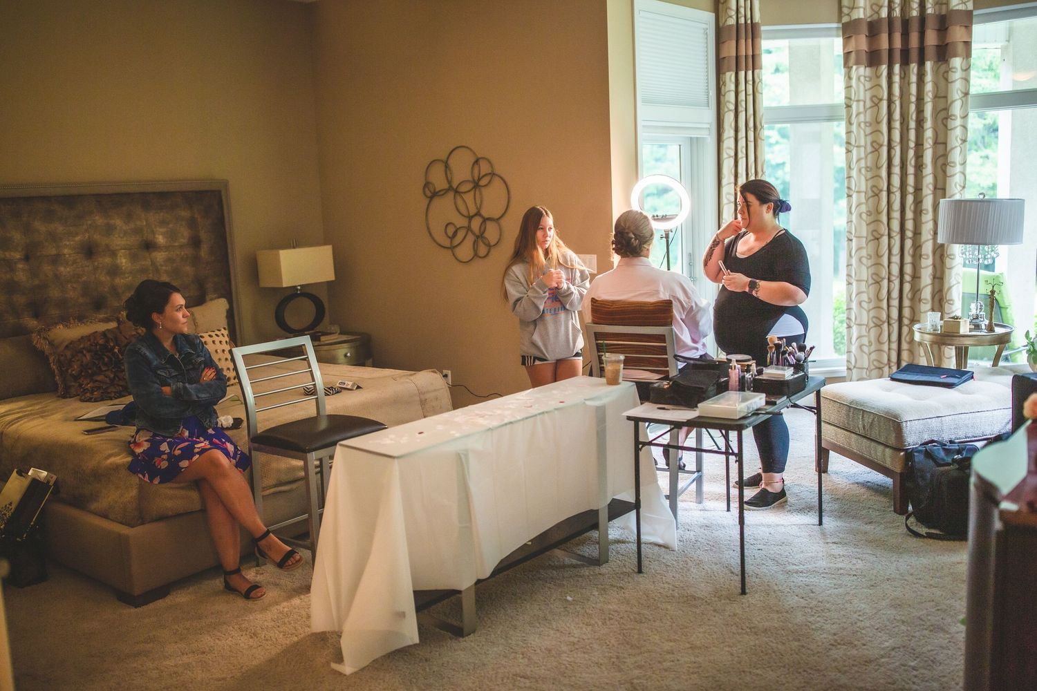 Wedding preparations take place in a cozy living room with a white-covered table and decorative stone wall.