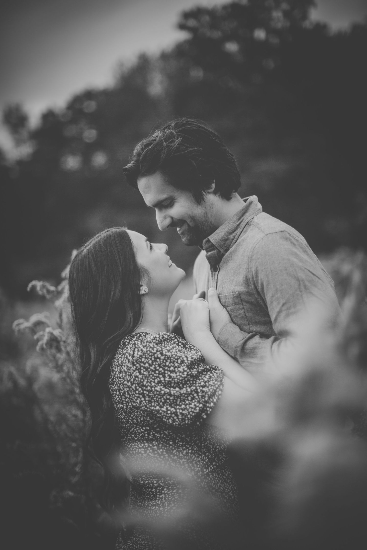 Black and white portrait of couple's intimate moment in natural setting.