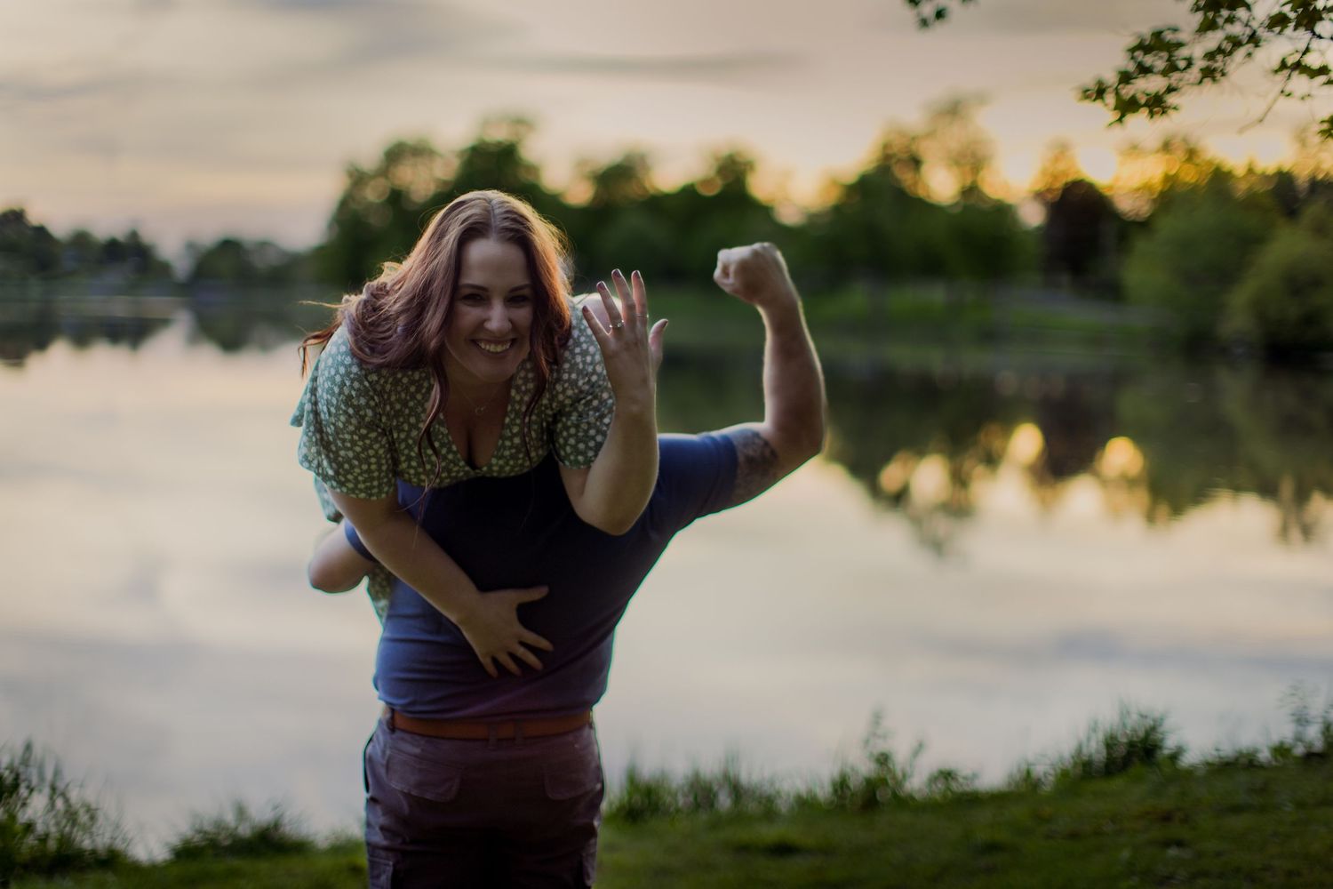 A couple shares a joyful moment by the water during golden hour.