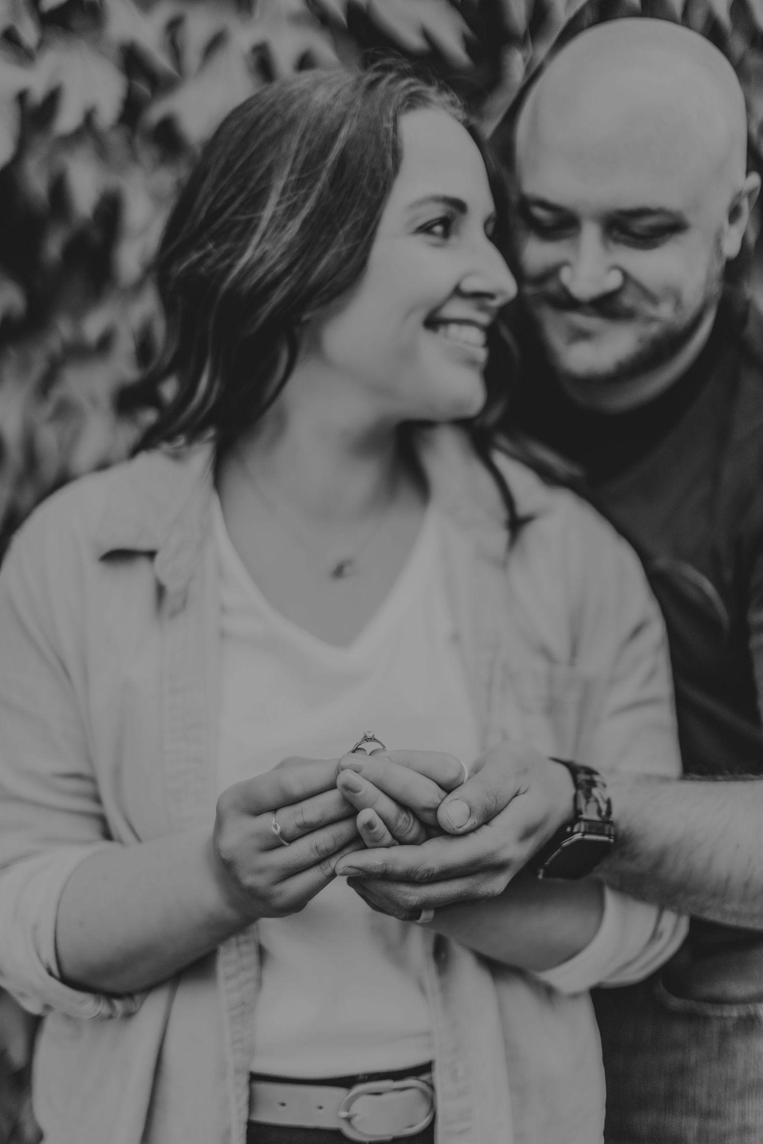 Black and white photo of couple sharing joyful moment while holding something between them.