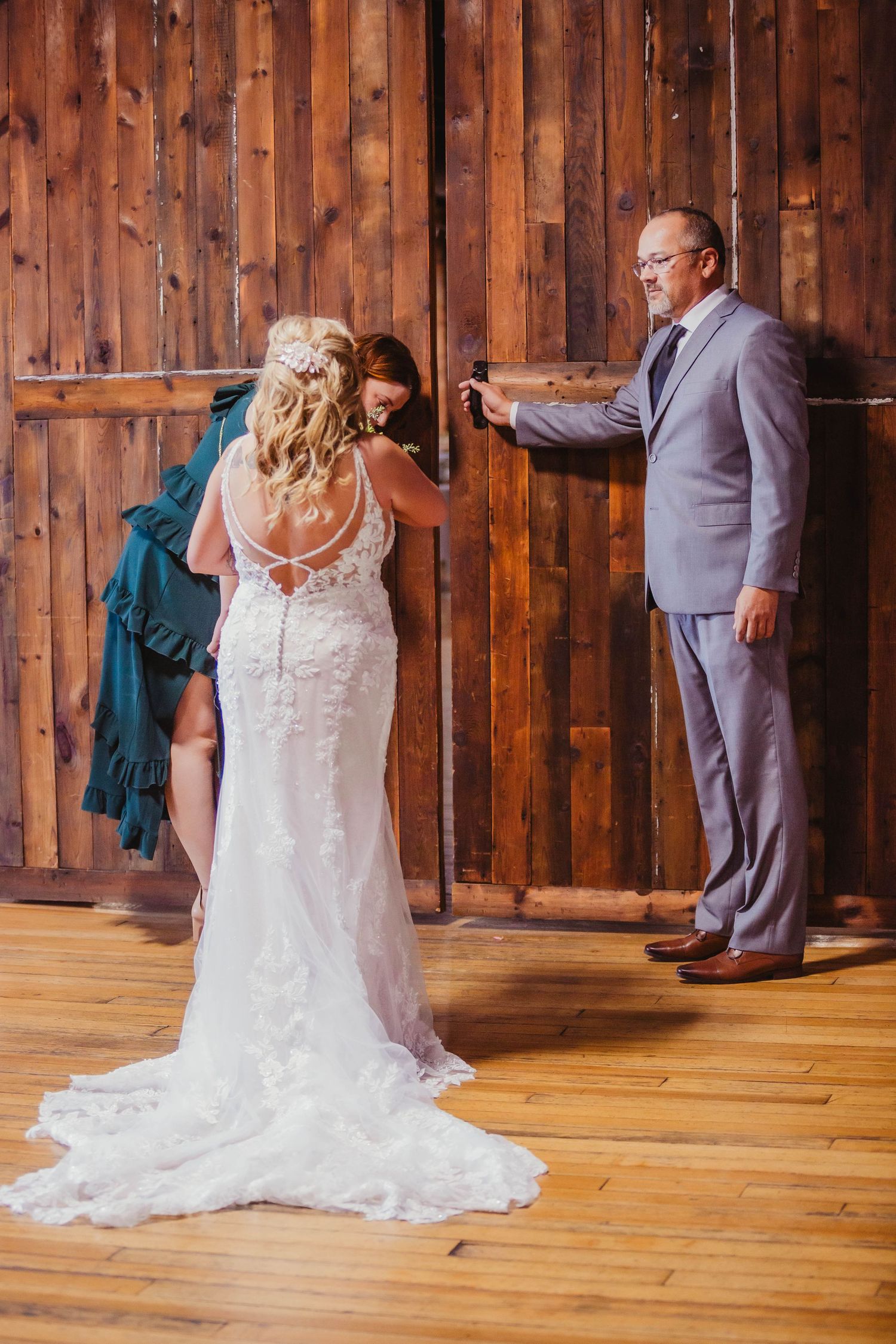 The bride's beautiful lace dress train flows across wooden floors as final preparations are made.