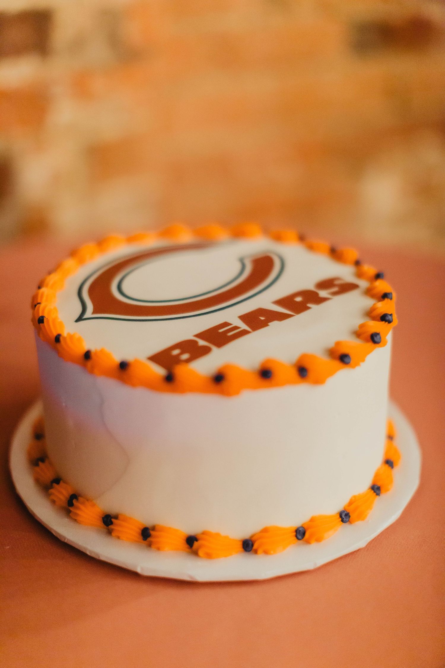 White round cake with orange trim featuring Chicago Bears logo design.