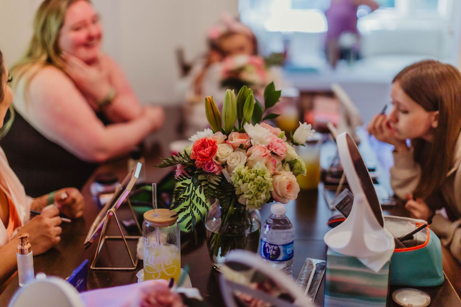 Wedding reception table with colorful floral centerpiece and guests enjoying celebration.