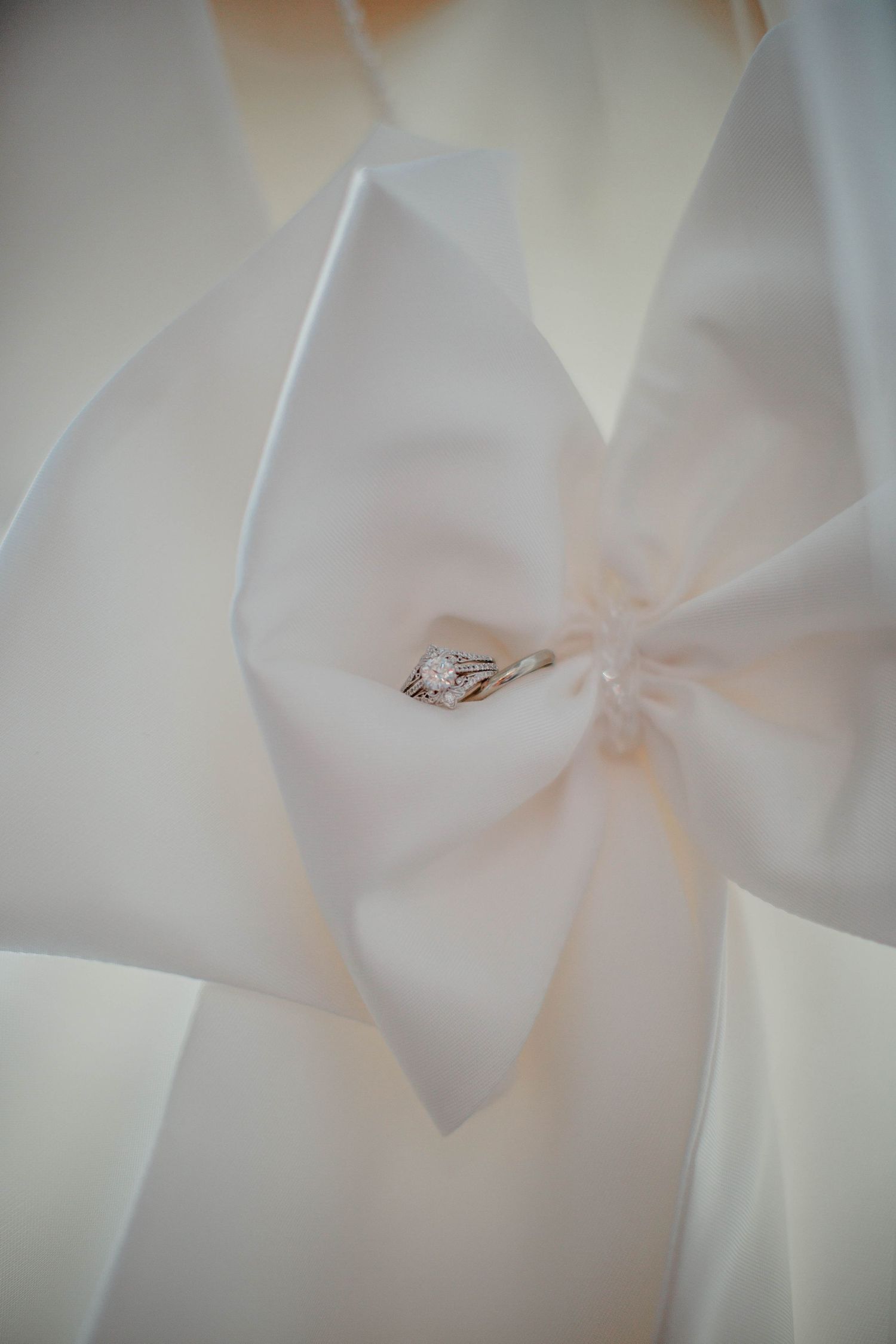 Diamond engagement ring nestled in white satin wedding dress fabric.