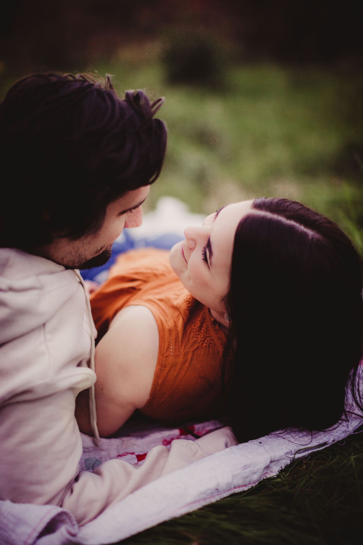 Intimate portrait session on a blanket in the grass with dramatic lighting.