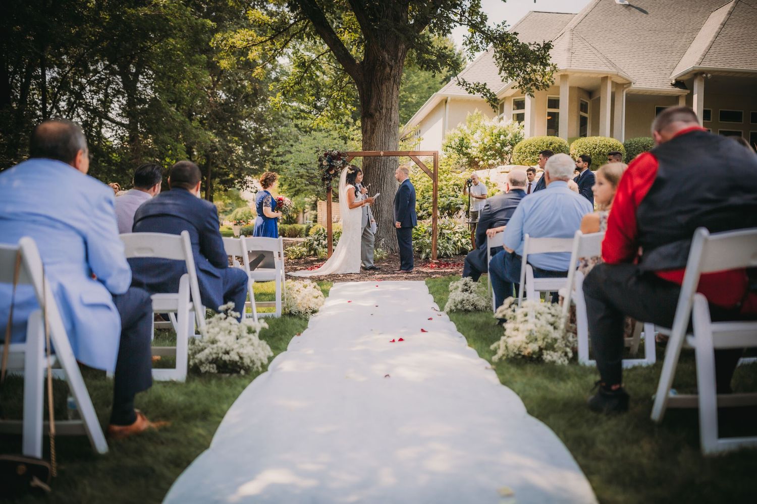 White folding chairs arranged in rows for an outdoor garden wedding ceremony.
