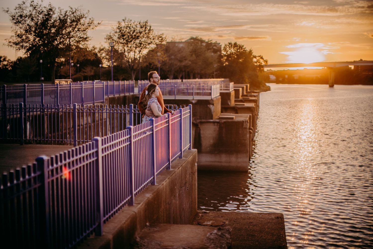 Stunning golden hour waterfront scene with metal railings and reflections on the calm water.