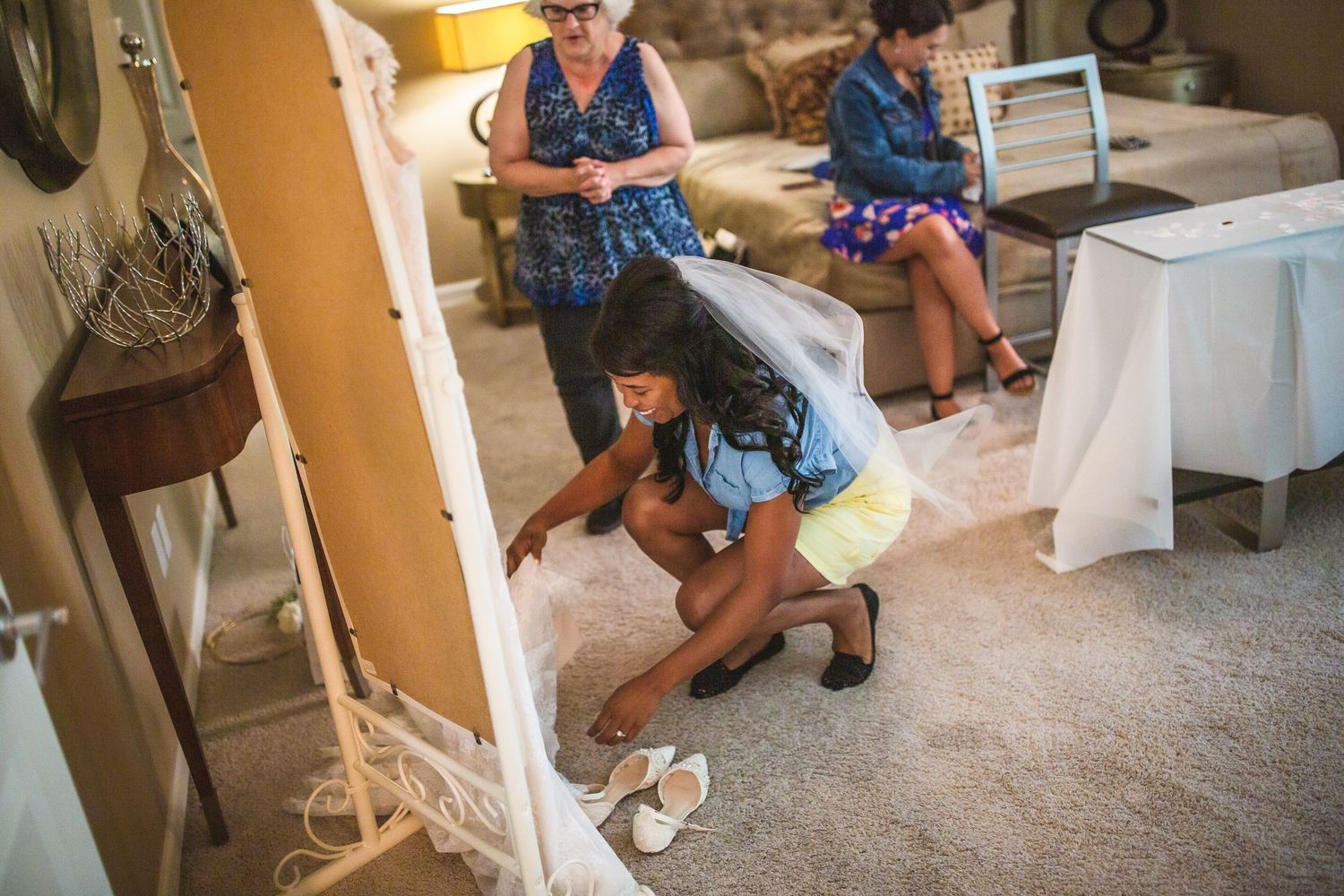 Wedding preparation scene showing someone adjusting details near white linens and shoes.
