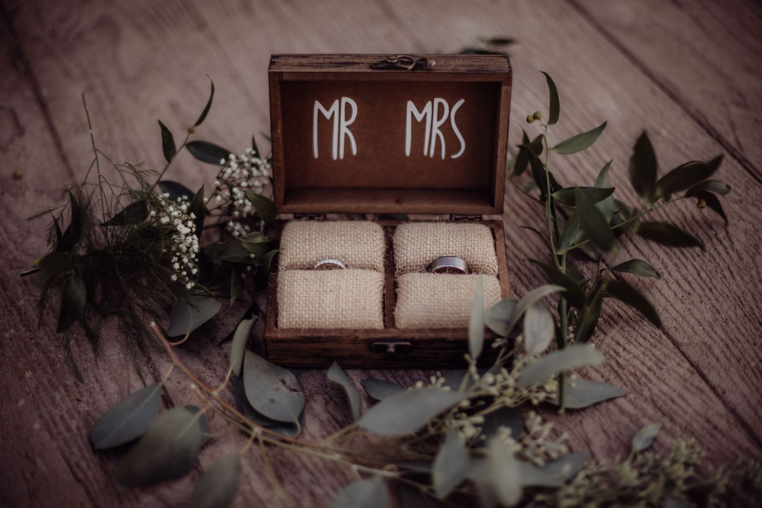 Rustic wooden wedding sign displaying 'Mr & Mrs' text with greenery decorations.