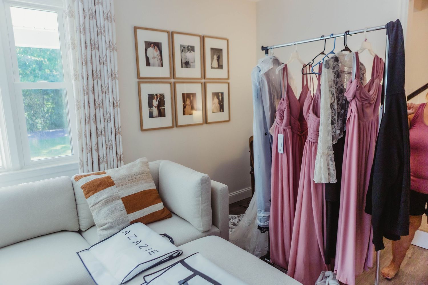 Sunlit room with pink dresses and decor arranged for wedding preparations.