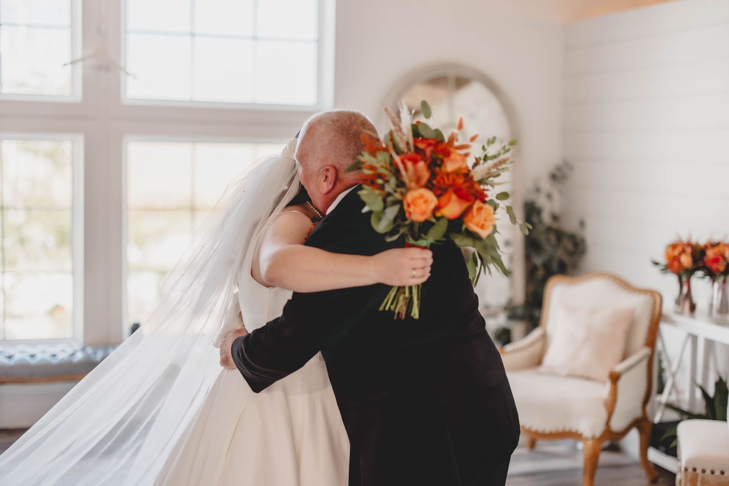 A tender embrace between newlyweds during their first look in an elegant white venue.