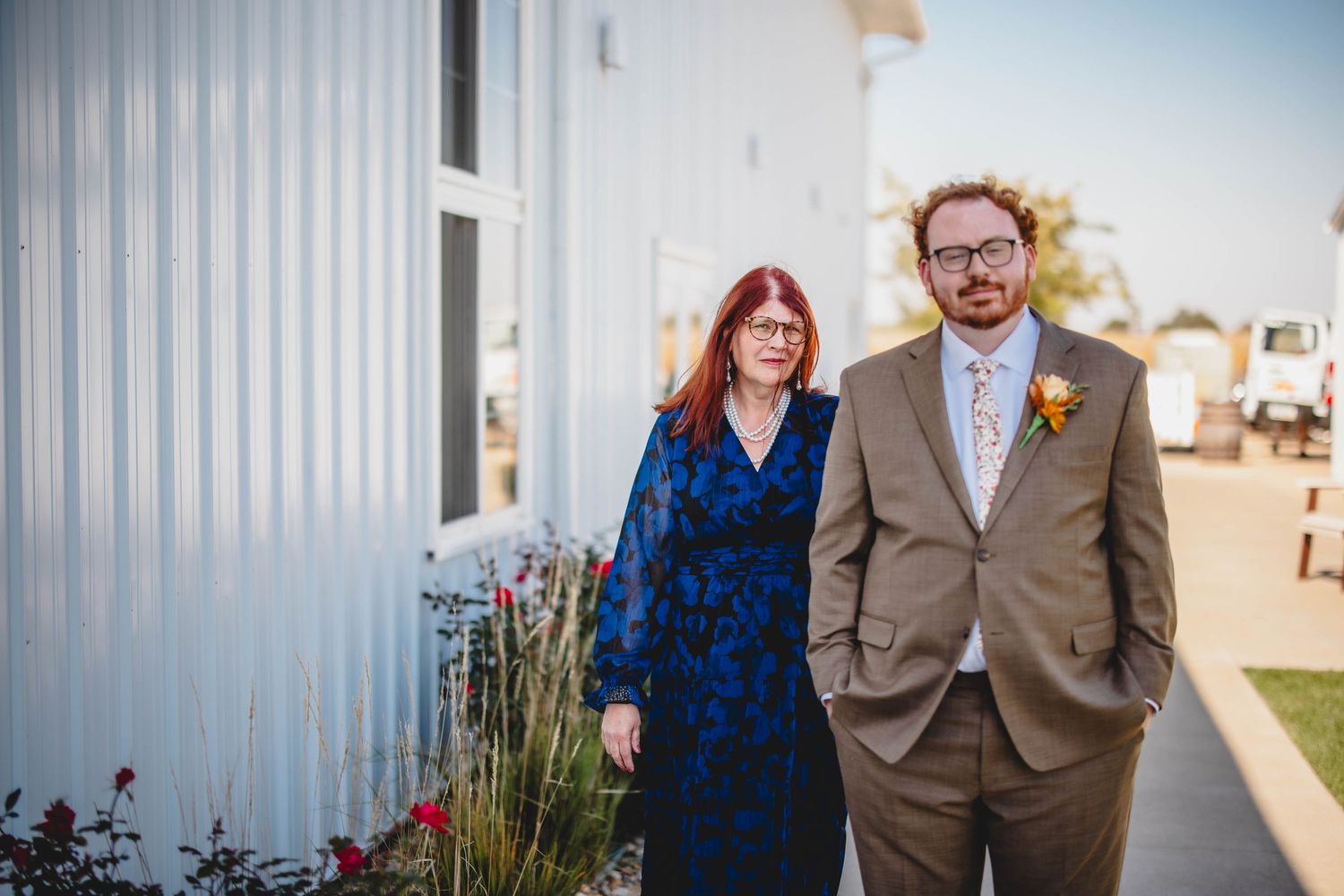 A couple in formal attire standing outside a white building.