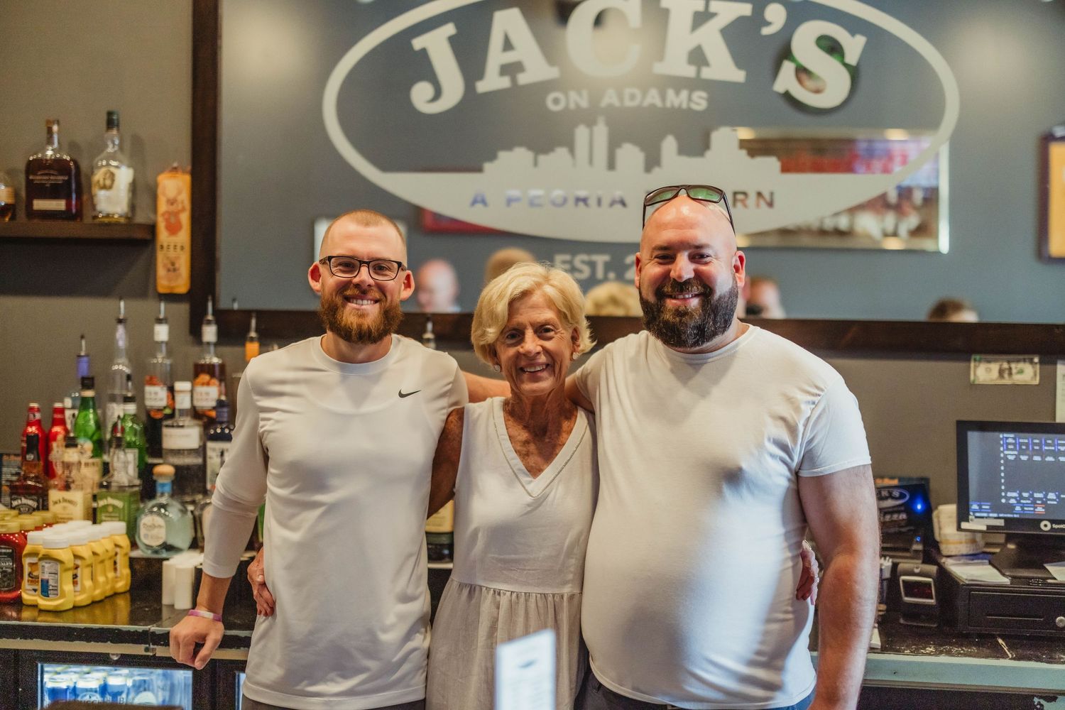 Staff members behind the bar at Jack's restaurant smiling warmly at camera.