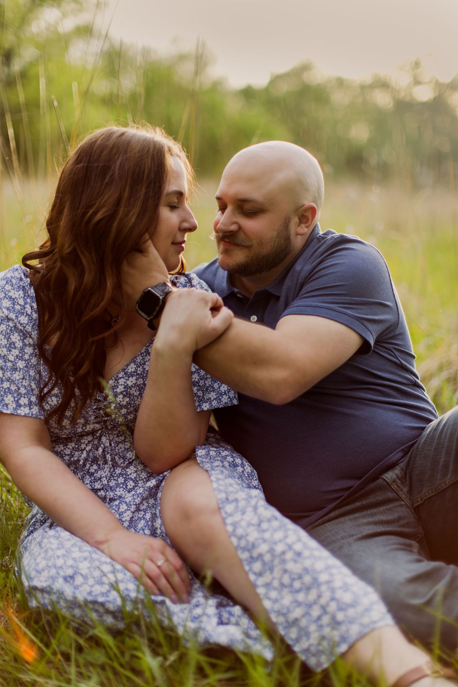 Couple lounging in meadow shows affection during springtime outdoor photo shoot.