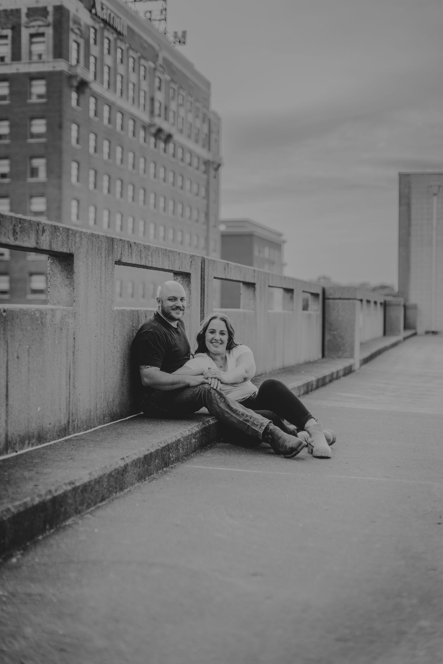 Black and white photo of a couple lounging on an urban rooftop.