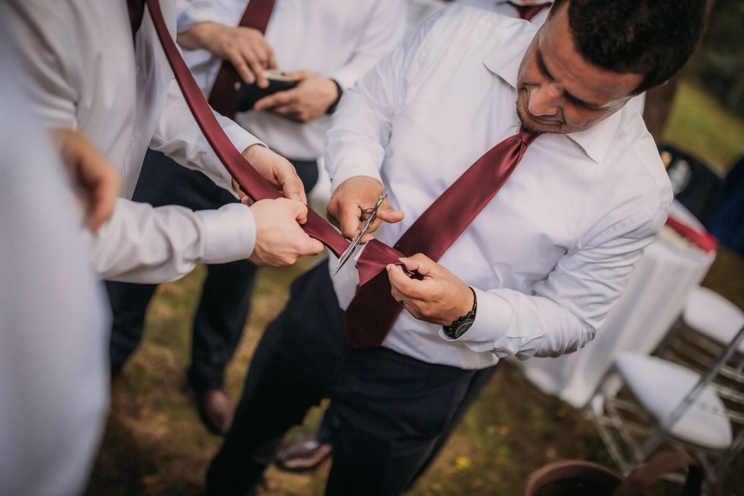 Group of formally dressed attendees gather to look at something during an outdoor celebration.