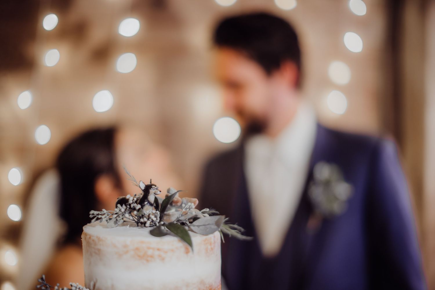 Detailed shot of a minimalist white wedding cake with grey botanical decorations.