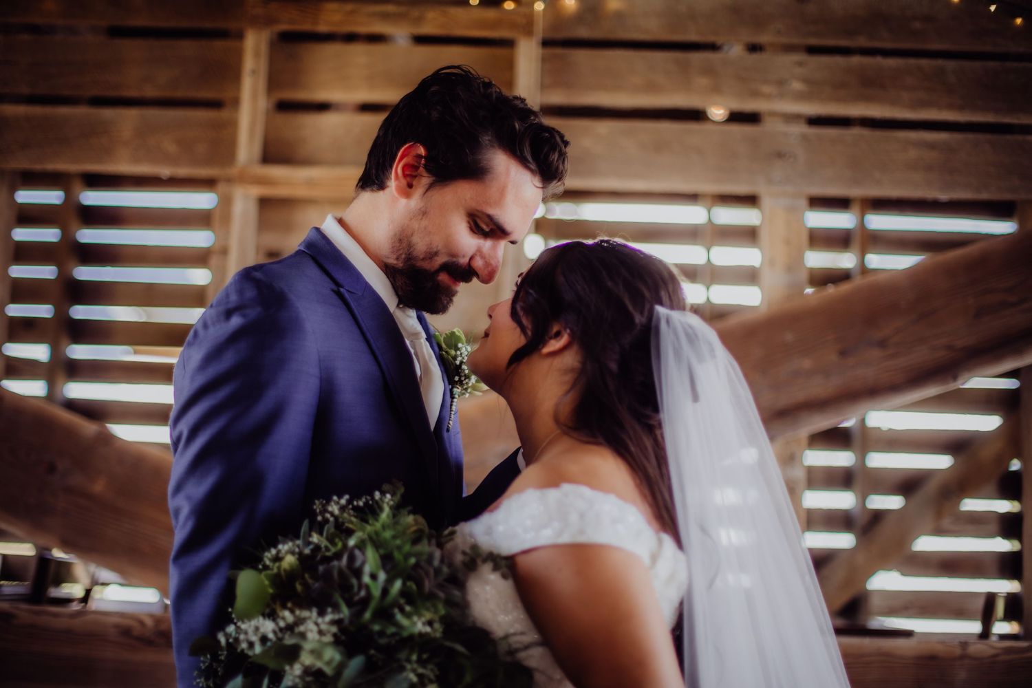 Sweet first look moment between newlyweds in a barn with wooden slat walls.