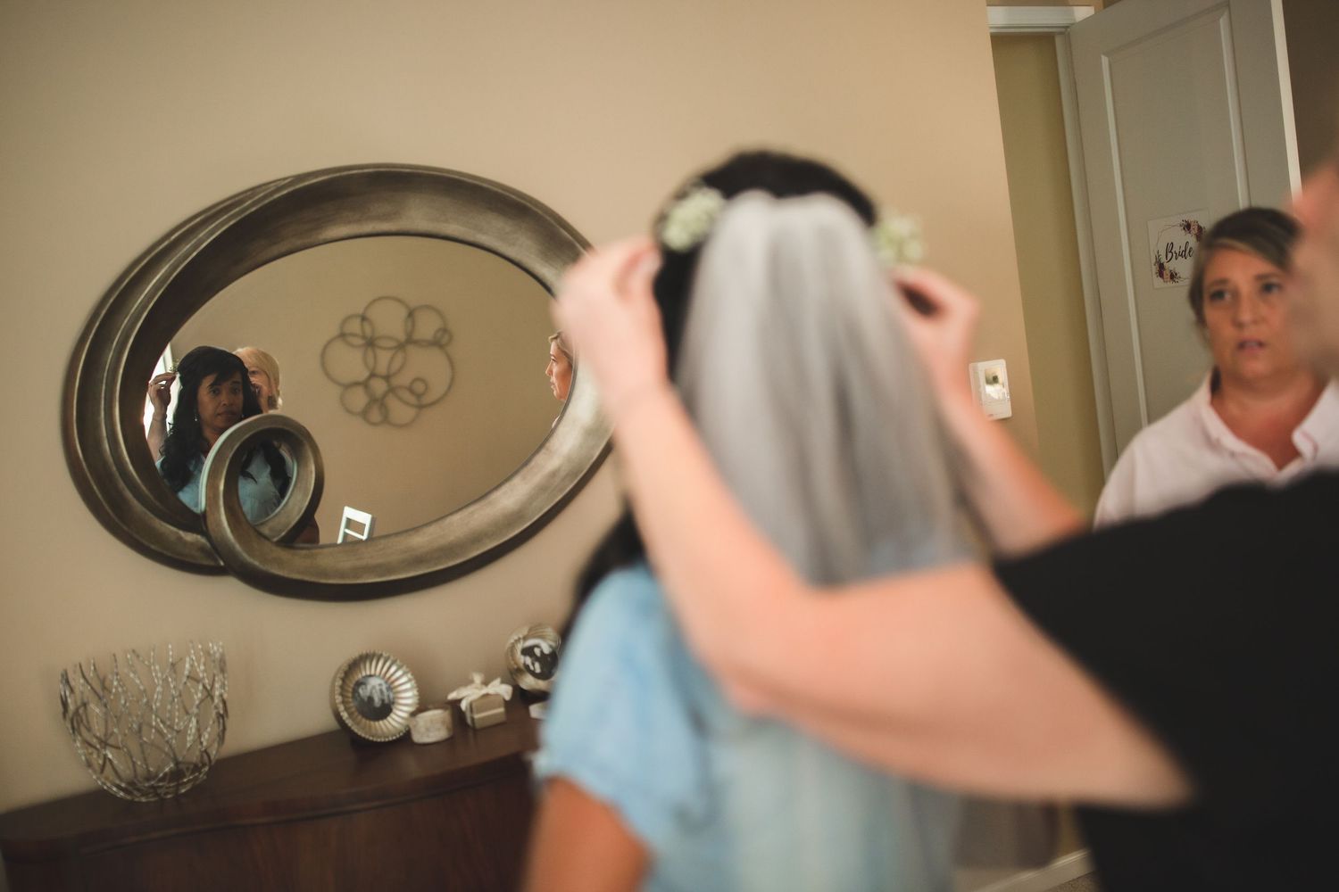 Mirror reflection captures intimate wedding prep moment as veil is positioned.