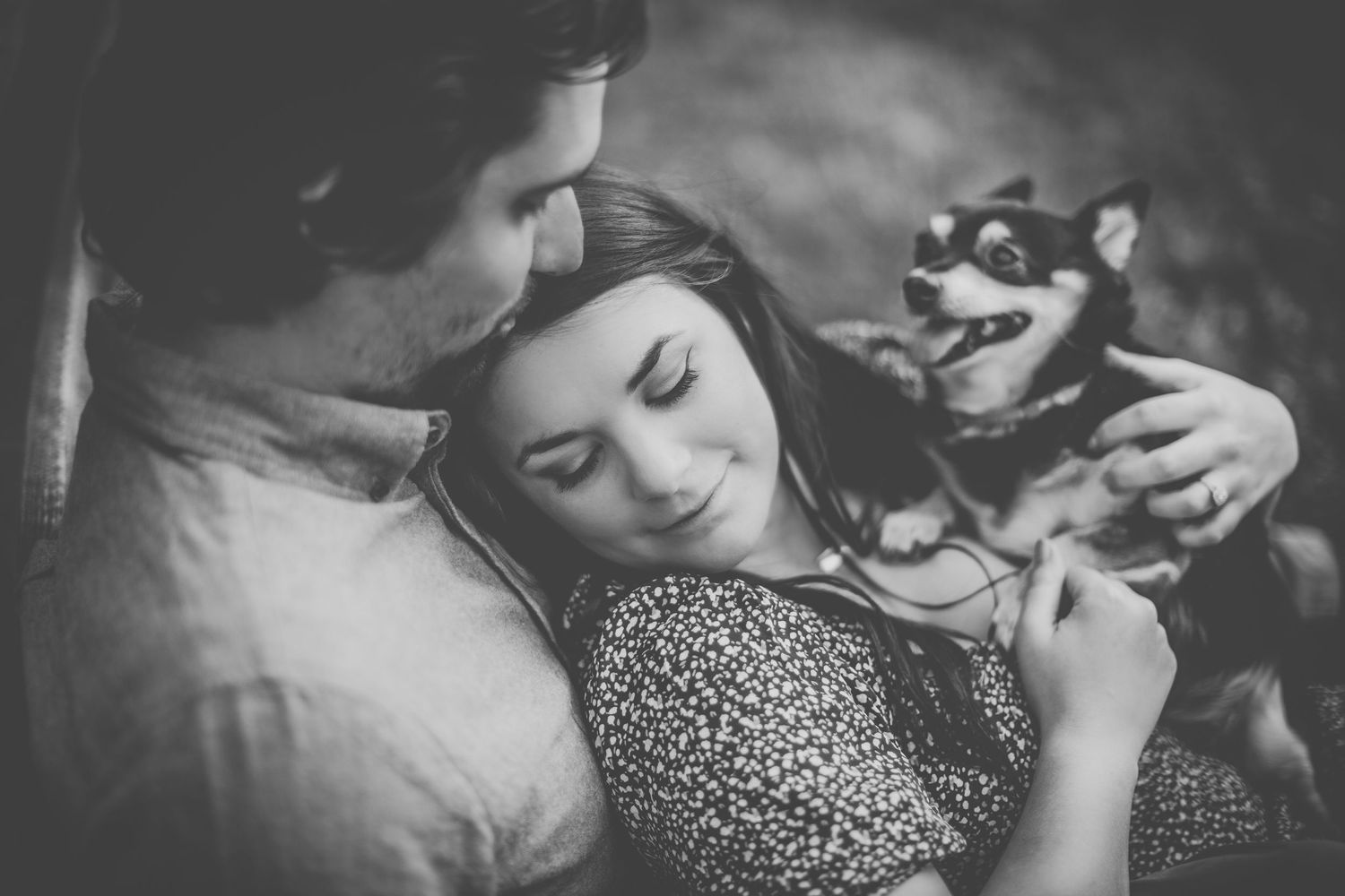 Couple and their pet dog share an intimate black and white moment while cuddling together.